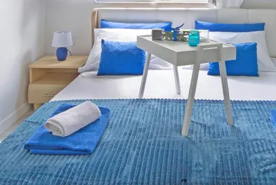 a bedroom with a bed with a table and a blue rug at Harmony in Radanovići