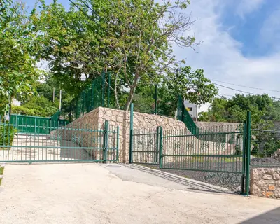 a green fence with a tree behind it at The White House in Ðurmani