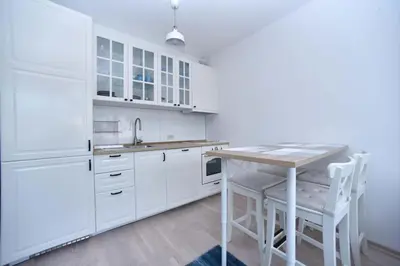 a white kitchen with a wooden table and white cabinets at Apartment Andrea in Budva