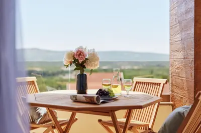 a table with a vase of flowers and wine glasses at Kotor Rooftop Apartments in Kotor