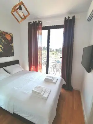 a bedroom with a large white bed with a balcony at Vegi Apartments in Bar
