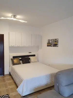 a bedroom with a white bed and a blue chair at Apartman Bečiči - Budva - Free Parking in Budva