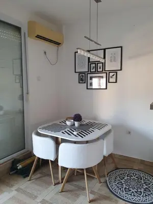 a dining room with a table and two white chairs at Apartman Bečiči - Budva - Free Parking in Budva