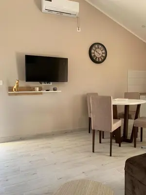 a dining room with a table and a clock on the wall at Lara i Mirko Apartments in Mrčevac