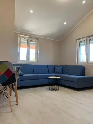 a blue couch in a living room with windows at Lara i Mirko Apartments in Mrčevac