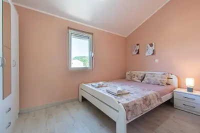 a bedroom with a bed and a window at Lara i Mirko Apartments in Mrčevac