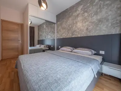 a bedroom with a large bed and a wall at Luxury modern apartment 8min walk from beach in Becici in Rafailovici