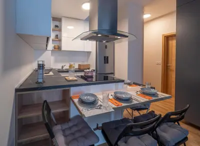 a kitchen with a island with a table with chairs at Luxury modern apartment 8min walk from beach in Becici in Rafailovici