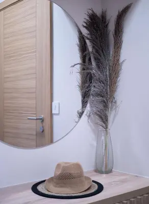 a hat and a vase on a table with a mirror at Luxury modern apartment 8min walk from beach in Becici in Rafailovici
