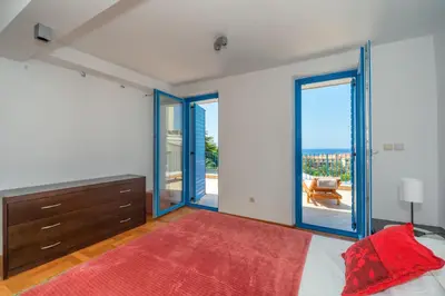 a bedroom with a bed with a dresser and sliding glass doors at Altomare with Sea View in Petrovac na Moru