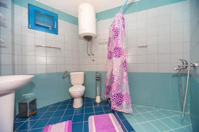 a bathroom with a toilet and a pink shower curtain at Altomare with Sea View in Petrovac na Moru