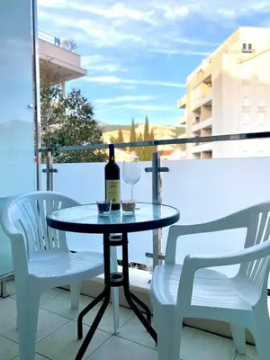 a table with a bottle of wine and two chairs at Aegean home budva vojvodanska 16 b stan7 in Budva