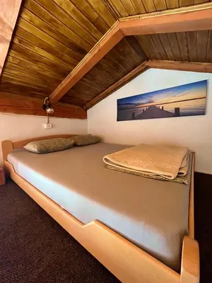 a bed in a room with a wooden ceiling at Apartman Boljević in Podgorica