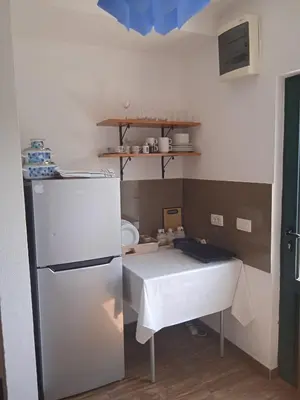 a small kitchen with a table and a refrigerator at Villa Elena Zagora in Neodi