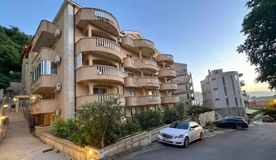 a large building with cars parked in front of it at Beach Bliss Apartment in Pržno