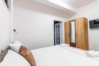a white bedroom with two beds and a tv at CASA BIANCA & Spa 2 in Ulcinj