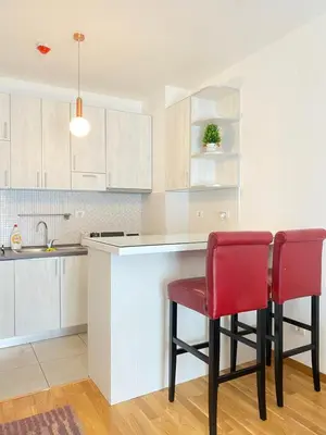 a kitchen with two red chairs at a counter at Apartman Vesna City 2. PG in Podgorica