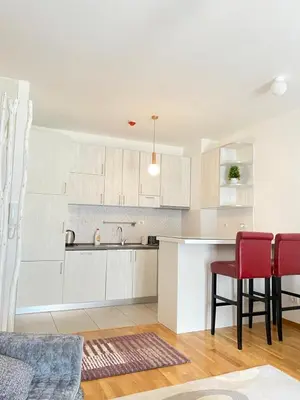 a kitchen with white cabinets and red chairs at Apartman Vesna City 2. PG in Podgorica