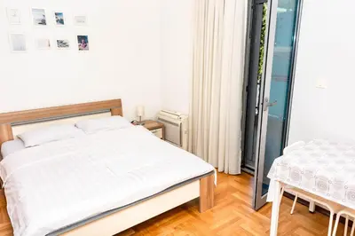 a bedroom with a bed and a table and a window at Bobo Apartment in Budva