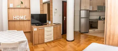 a room with a kitchen with a tv and a table at Bobo Apartment in Budva
