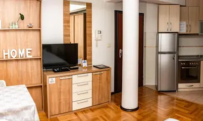 a kitchen with a tv and a pole in a room at Bobo Apartment in Budva
