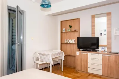 a living room with a table and a tv at Bobo Apartment in Budva