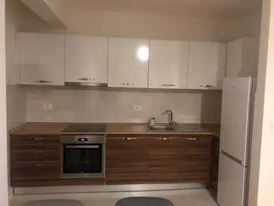 a kitchen with white cabinets and a sink and a refrigerator at Stan Central point Podgorica in Podgorica