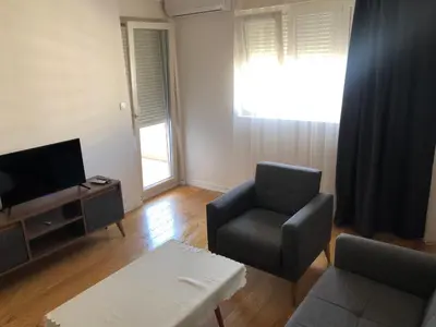 a living room with a chair and a television at Stan Central point Podgorica in Podgorica