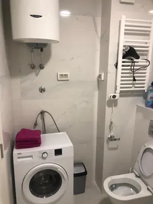a small bathroom with a washing machine and a toilet at Stan Central point Podgorica in Podgorica