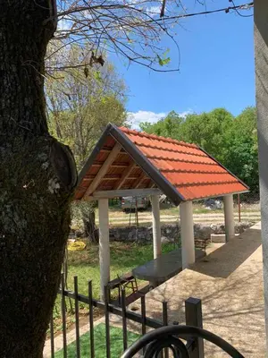 a bench with an orange roof next to a tree at Bandici house in Podgorica