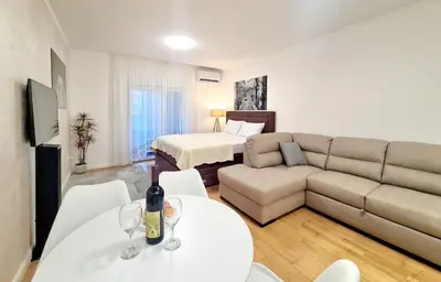 a living room with a couch and a table with wine glasses at Becici Studio Apartment in Budva