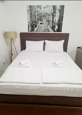 a bed with white sheets and a black and white picture on the wall at Becici Studio Apartment in Budva
