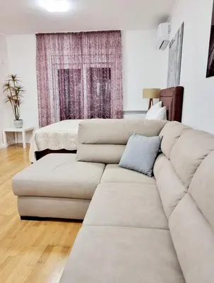 a white living room with a couch and a bed at Becici Studio Apartment in Budva