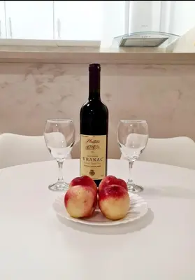 two apples on a plate with a bottle and two glasses at Becici Studio Apartment in Budva