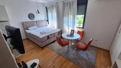 a small room with a bed and a table and chairs at Lijepo pozicioniran stan, atrakcije blizu in Podgorica