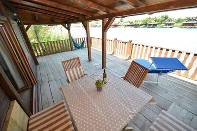 a table and chairs on a wooden deck with a table and a blue table at Filipa River House Ada Bojana in Ulcinj
