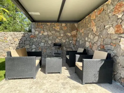 a patio with chairs and a stone wall at Villa Pine in Bar