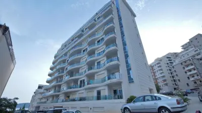 a large white building with cars parked in front of it at Ambassador Apartment Bečići with Private Garage Parking in Becici
