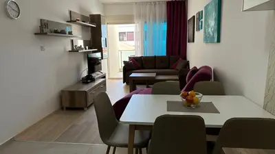 a living room with a table and chairs and a living room at Ambassador Apartment Bečići with Private Garage Parking in Becici