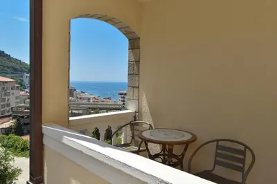 a balcony with a table and chairs and a window at Apartmani Bojana in Budva