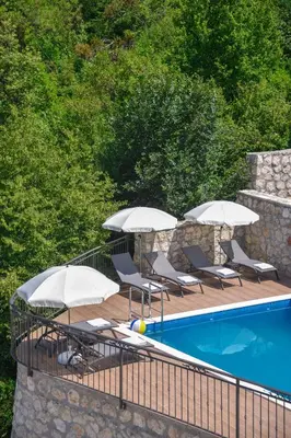a swimming pool with two umbrellas and chairs next to a swimming pool at Villa Andrea 1 in Budva