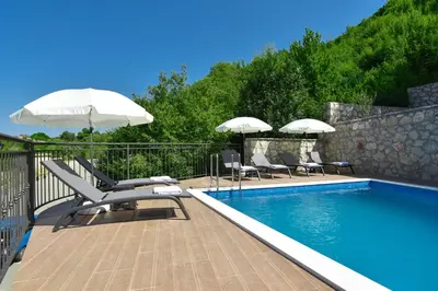 a swimming pool with chairs and umbrellas on a deck at Villa Andrea 1 in Budva