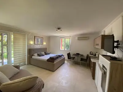 a bedroom with a bed and a living room with a table at Apartments Stankovic & Boat tours in Virpazar