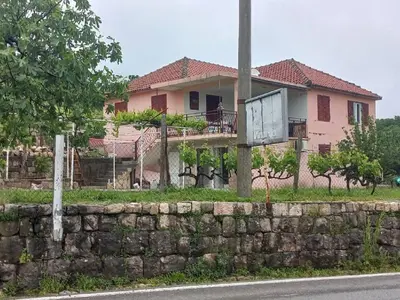 a house on the side of a road with a stone wall at Apartments Stankovic & Boat tours in Virpazar