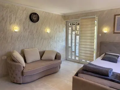 a bedroom with a couch and a bed and a clock at Apartments Stankovic & Boat tours in Virpazar