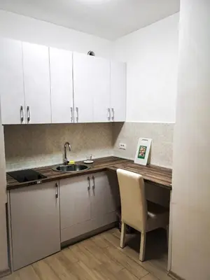 a kitchen with white cabinets and a sink and a chair at Apartment Queen Milena in Budva