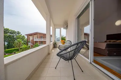a room with a balcony with a bed and a chair at Sotto Sole apartment in Bar