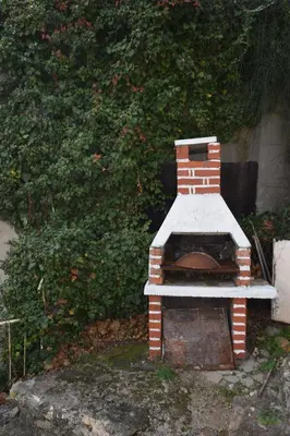 a brick oven sitting in front of a bush at Family Guest House in Ulcinj