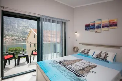 a bedroom with a bed and a balcony with a view at Fortress View apartment II in Kotor