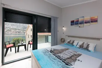 a bedroom with a bed and a balcony with a table at Fortress View apartment II in Kotor